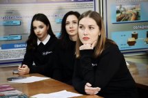 Три молоді жінки сидять за партою, серйозно сприймаючи подану інформацію та готуючись до можливих запитань чи дискусії.