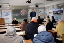 Аудиторія слухає чоловіка. Учасники уважно стежать за виступом, роблять нотатки.