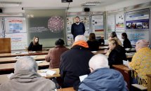 Аудиторія слухає чоловіка. Учасники уважно стежать за виступом, роблять нотатки.