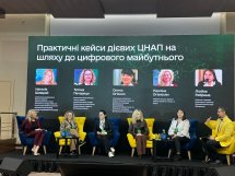 Панельна дискусія на конференції, спікери сидять у жовтих кріслах на сцені.