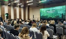 Вид на конференц-зал із великою кількістю учасників і сценою.
