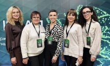 Групове фото п’яти жінок у конференц-зоні з зеленою стіною позаду.