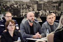 Ділова зустріч: Четверо людей сидять за столом, обговорюючи питання на тлі міського пейзажу.