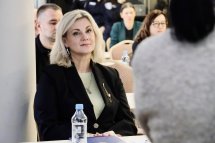 Учасниця конференції уважно слухає, поруч з нею  пляшка води.