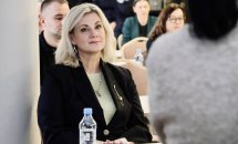 Учасниця конференції уважно слухає, поруч з нею  пляшка води.