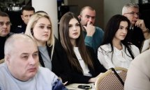 Люди уважно слухають спікера, сидячи за столами.