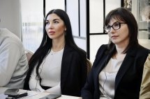 Три жінки на конференції: Жінки у ділових костюмах уважно слухають виступ.