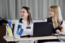 Дві жінки знаходяться в офісі. Вони посміхаються