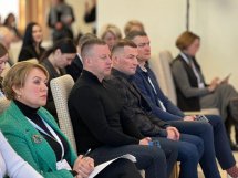 Люди сидять у залі, слухаючи доповідь