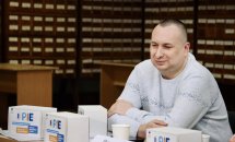  Чоловік у білій кофті. Він презентує звукові маячки Пай