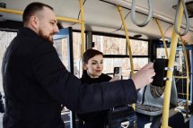У тролейбусі чоловік оплачує проїзд карткою для безконтактної оплати, а жінка поруч знімає цей процес на телефон