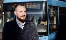 Чоловік стоїть на вулиці. На задньому плані видно тролейбус