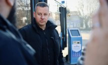 Чоловік стоїть на вулиці,  на задньому плані видно тролейбус і термінал.