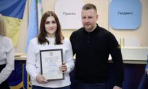 Чоловік та жінка, яка тримає у руках почесну грамоту.