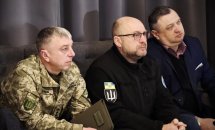 Троє чоловіків слухають доповіді на діалоговій зустрічі.