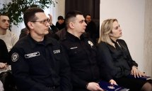Двоє чоловіків та жінка присутні на діалоговій зустрічі та слухають.