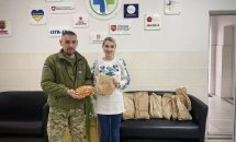 Жінка у вишиванці та чоловік у військовій формі позують з хлібом.