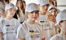 Діти у футболках посміхаються.