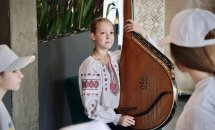 Дівчинка у вишиванці грає на бандурі.