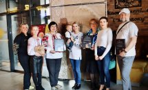 Група людей позують на фоні банера, тримаючи у руках подяки.
