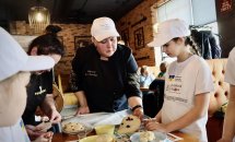 Жінка у чорному одязі допомагає дітям працювати з тістом.