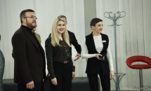 Кілька людей спілкуються у просторому приміщенні з білими шторами.