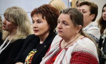 Жінки у вишитих сорочках сидять у залі.