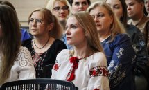 Жінки у вишитому одязі сидять у залі.