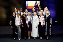 Група жінок у вишиванках позують для фото, на задньому фоні - екран.
