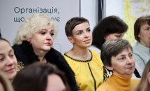 Група жінок сидять у приміщенні.