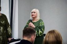 Жінка у вишитій сукні тримає мікрофон у руках.