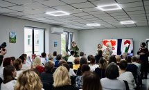 Захід у залі: учасники слухають виступ на тлі екрана з ілюстраціями.