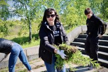 Жінка у сонцезахисних окулярах тримає бур'яни у руках.