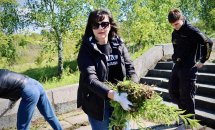 Жінка у сонцезахисних окулярах тримає бур'яни у руках.