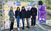 Хлопець та чотири жінки позують біля банера.