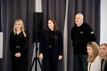 Дві жінки та чоловік стоять у приміщенні.