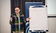 Чоловік стоїть біля фліпчарту, на якому написано 'Правила' та перше правило — 'Взаємоповага'.