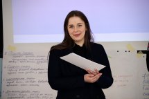 Жінка тримає у руках папір та посміхається.