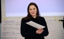 Жінка тримає у руках папір та посміхається.