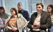 Люди сидять у приміщенні та дивляться прямо перед собою.