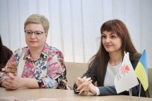 Дві жінки сидять за столом у приміщенні.