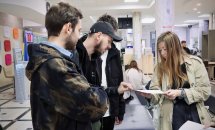 Жінка та троє чоловіків розглядають щось на папері.