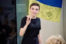 Жінка у чорному одязі щось розповідає.