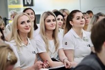 Багато жінок у білому одязі сидять у приміщенні.