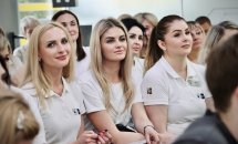 Багато жінок у білому одязі сидять у приміщенні.
