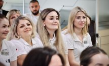 Жінки в уніформі з бейджами уважно слухають під час заходу.