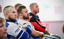 Група чоловіків сидить у приміщенні.