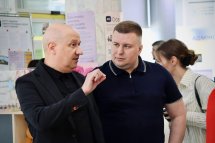 Двоє чоловіків перебувають у приміщенні, один щось розповідає.