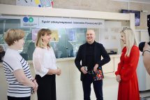 Три жінки та чоловік посміхаються в приміщенні.