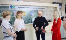 Три жінки та чоловік посміхаються в приміщенні.